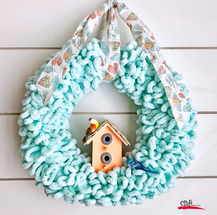 pretty blue spring wreath made from hook yarn with birdhouse
