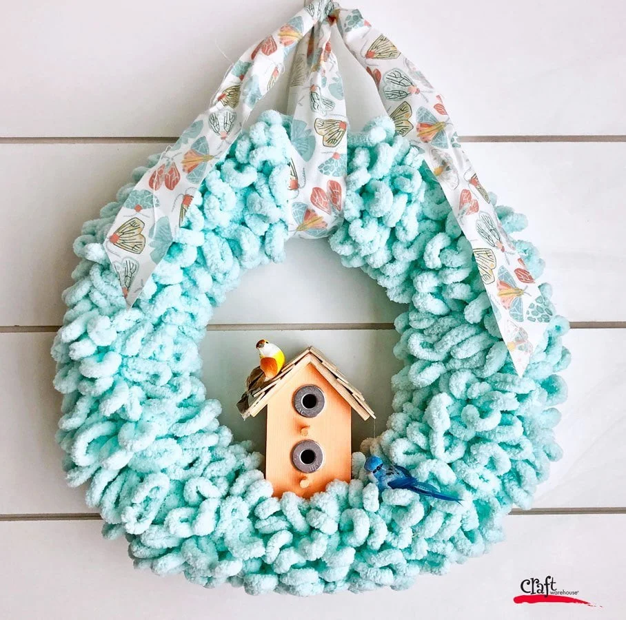 pretty blue spring wreath made from hook yarn with birdhouse