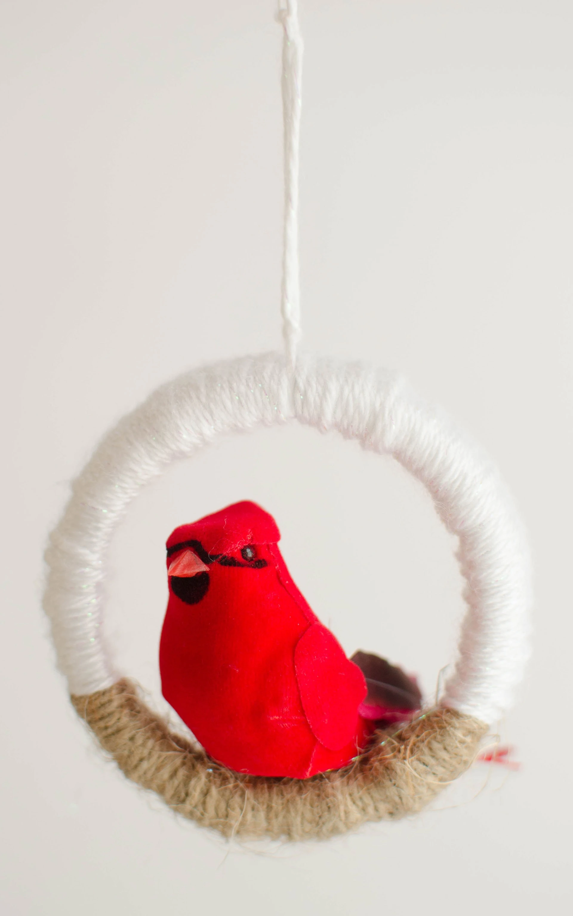 This bird ornament is so pretty and super easy to make. Use your leftover mason jar lids and some yarn, plus an inexpensive craft bird from the Dollar Tree and you're all set! Click through to see how to make this easy mason jar lid ornament.#DIYChristmasOrnaments #HandmadeHolidays #CardinalLove
