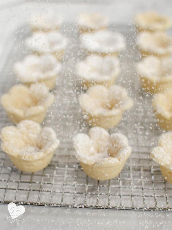 flower cookie cups being sprinkled with powdered sugar