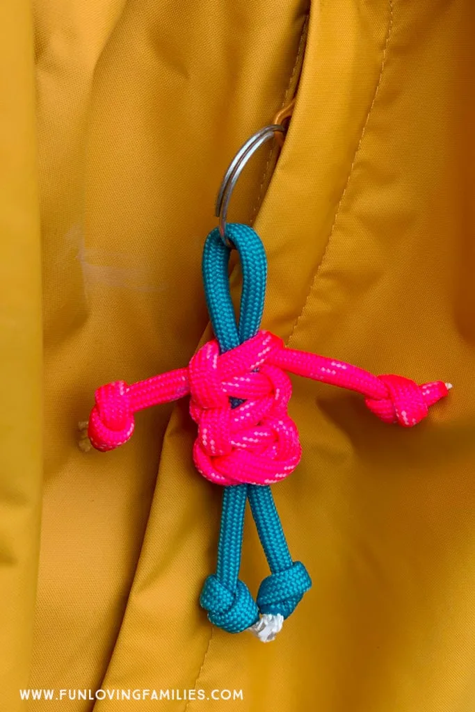 Pink and teal lanyard buddy hanging from zipper. 