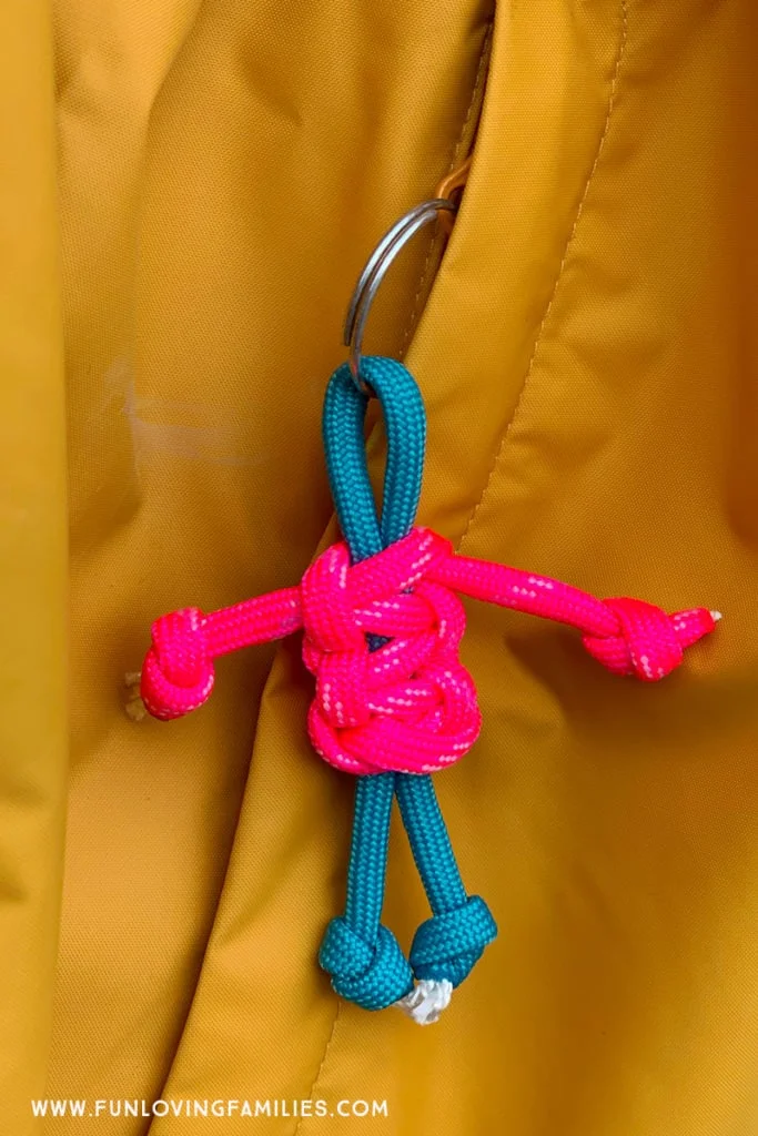 Pink and teal lanyard buddy hanging from zipper.