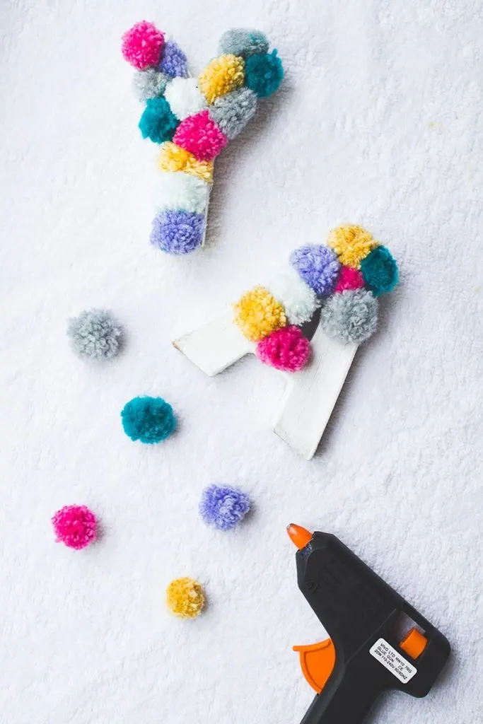 colorful pom pom letters and hot glue gun