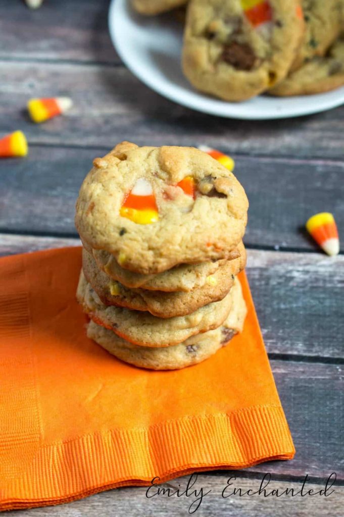 stack of candy corn cookies on orange napkin with plate of cookies in the background