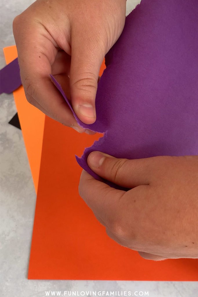 hands tearing purple paper