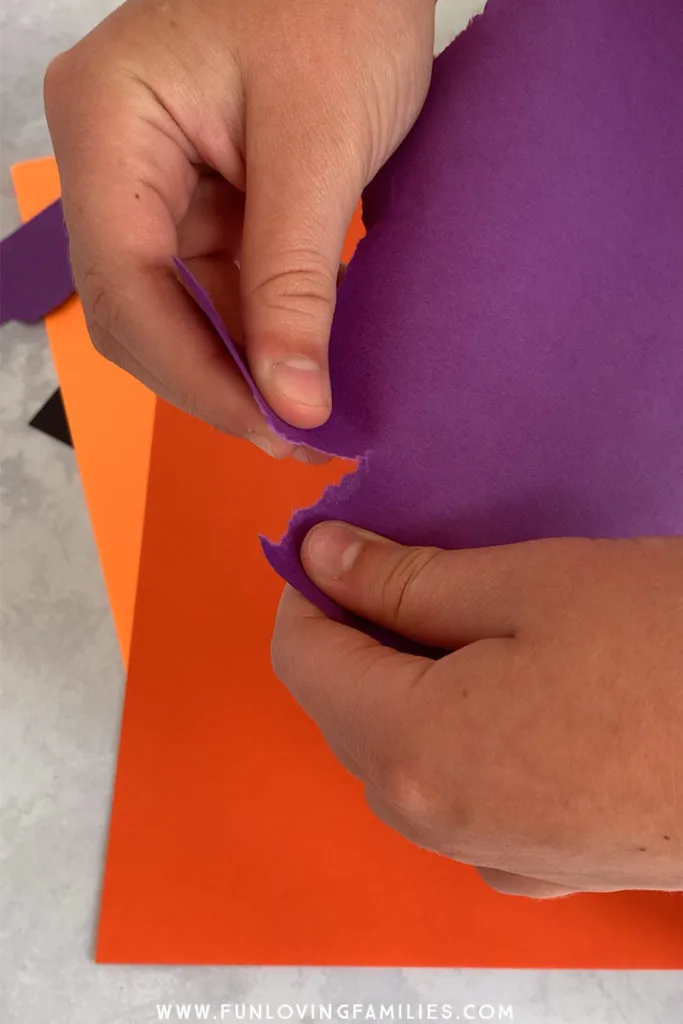 hands tearing purple paper