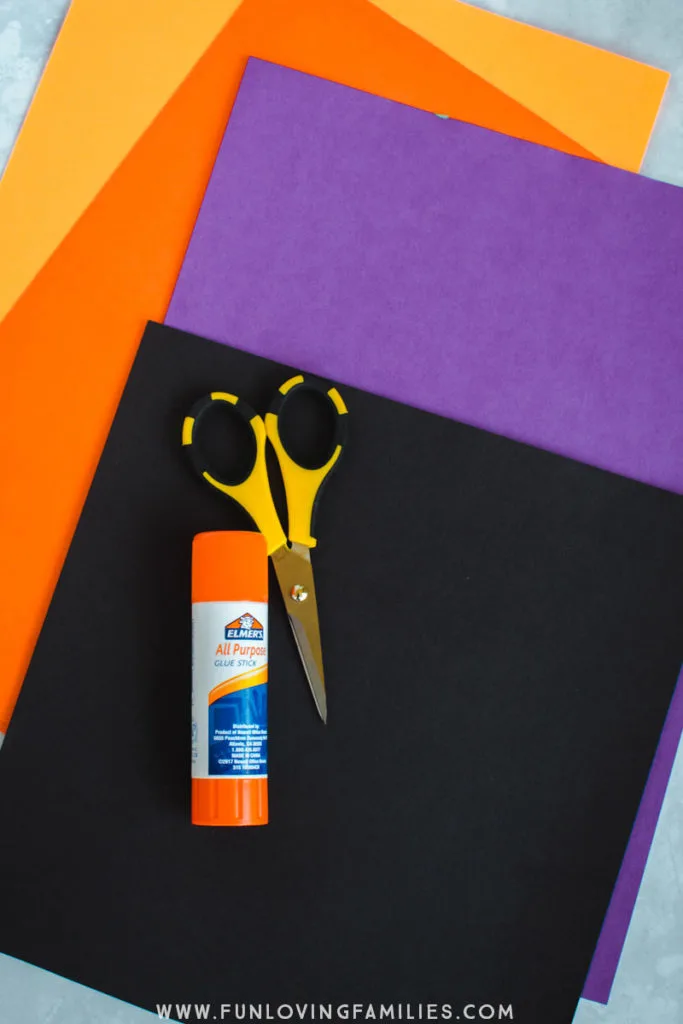 orange, purple, and black paper with scissors and glue stick