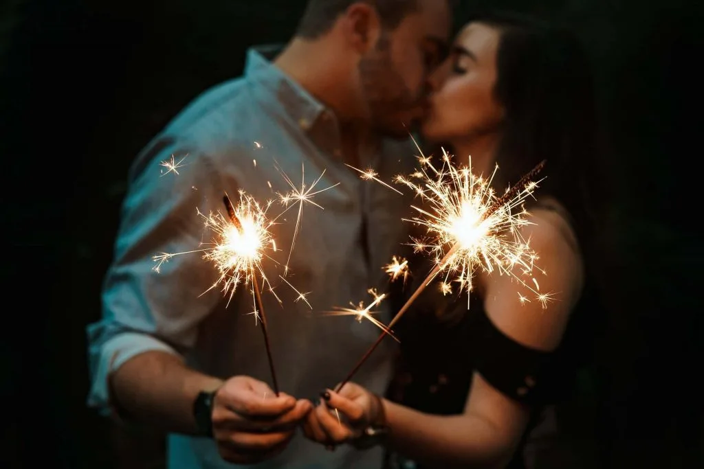 Couple kisses holding sparklers on romantic summer night